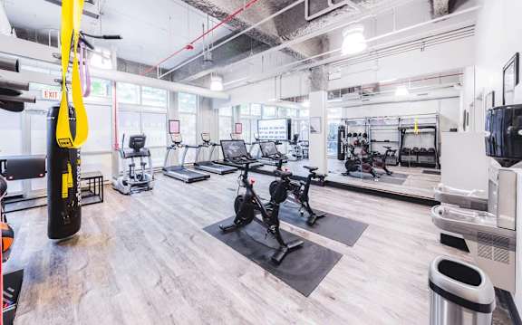 A gym with a variety of equipment including a treadmill, a stationary bike, and a punching bag.