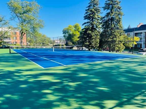 A tennis court surrounded by trees and buildings.