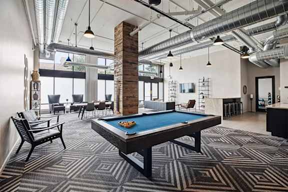 A room with a pool table and a brick pillar.