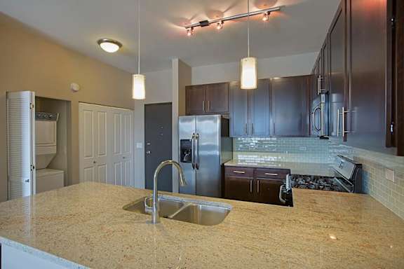 A kitchen with a granite countertop and stainless steel appliances.