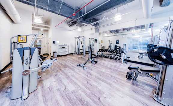 A gym with a variety of equipment including a rowing machine, a treadmill, and a weight bench.