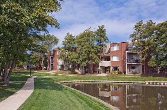 A modern apartment complex with a pond in front.