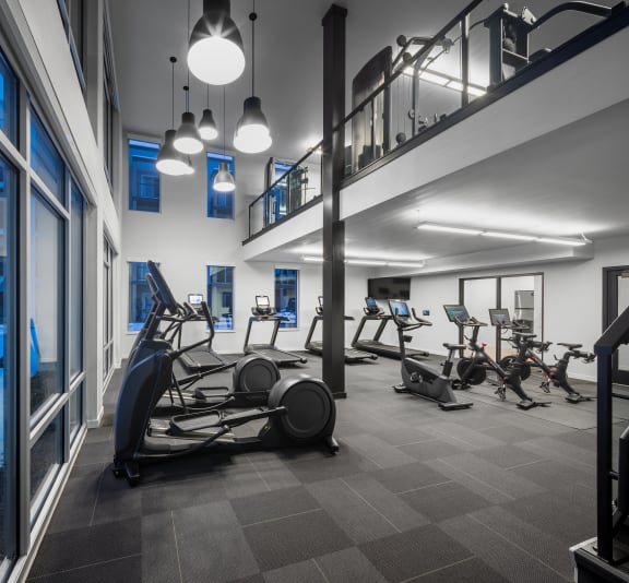 a gym with cardio machines and weights in a building with a staircase at 2929 on Mayfair, Wauwatosa, Wisco