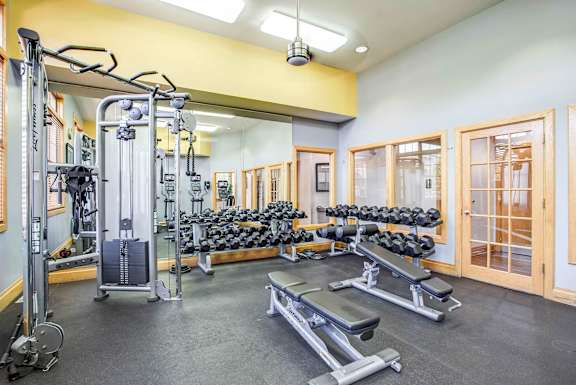 A gym with a variety of equipment including weights and benches.