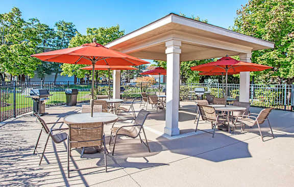 A patio with tables and chairs under red umbrellas.
