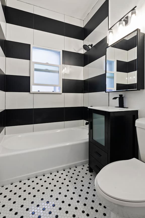 A black and white bathroom with a white toilet and a black cabinet.