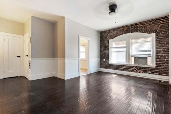 A studio apartment with a brick wall and wooden floors.