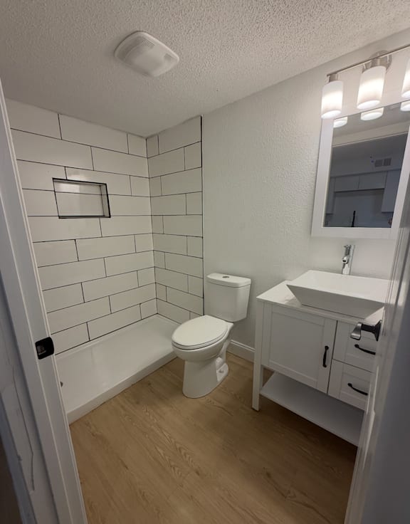 A white toilet sits in a bathroom with a white sink and a mirror.