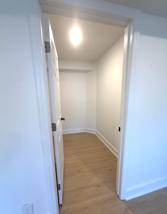 A white doorway leads to a room with wood flooring.