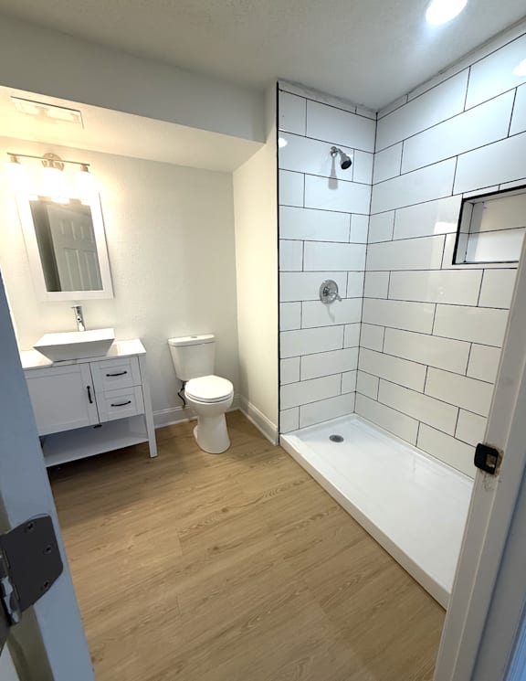 A white bathroom with a toilet, sink, and shower.