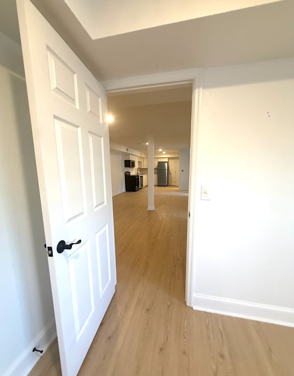 A hallway with a white door on the left and a white door on the right.
