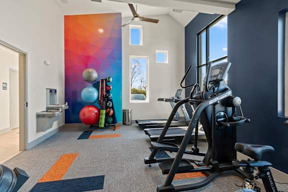 Fitness center at The Canvas apartments in Nashville, TN with a rowing machine, a treadmill, a weight bench, a medicine ball, a squat rack, a dumbbell, a kettlebell, a foam roller, a resistance band