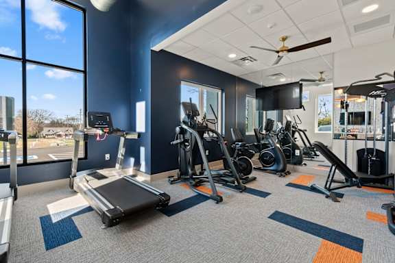 Apartment fitness center at The Canvas Apartments Nashville with a variety of equipment including treadmills, weights, and a television.