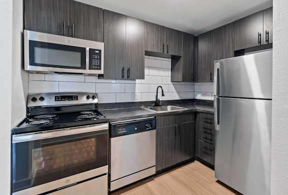 A modern kitchen with stainless steel appliances and wooden cabinets at The Canvas Apartments one and two bedroom apartments in Nashville, TN.