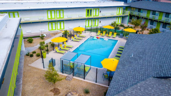 aerial shot of community pool and sundeck at Fusion apartments in Las Vegas, NV with lounge chairs and umbrellas