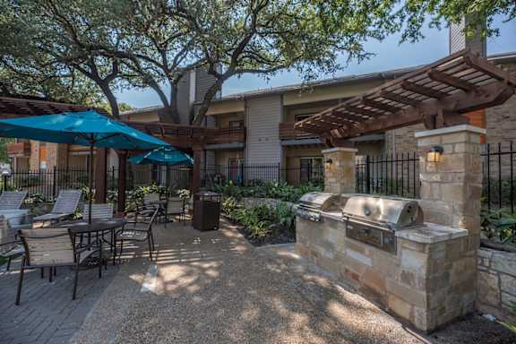 A patio with a grill and chairs under a canopy.