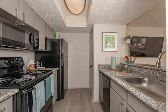 Fusion 35 kitchen with modern black stove top oven, refrigerator, and dishwasher.