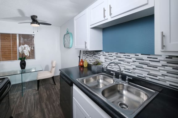Kitchen in Fifteen 50 apartments in Las Vegas with stainless steel sink, ceiling fan, and tile backsplash,