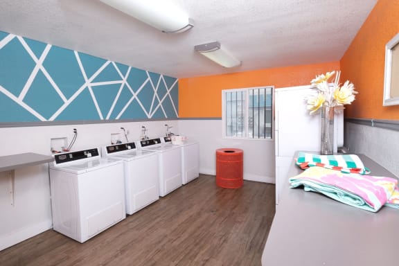 Brand new on-site laundry room at Fifteen 50 apartments in Las Vegas with many laundry machines and clean wood floor.
