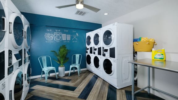 on-site laundry room at fusion Orlando furnished apartments with large washers and dryers and waiting area with table and chairs.