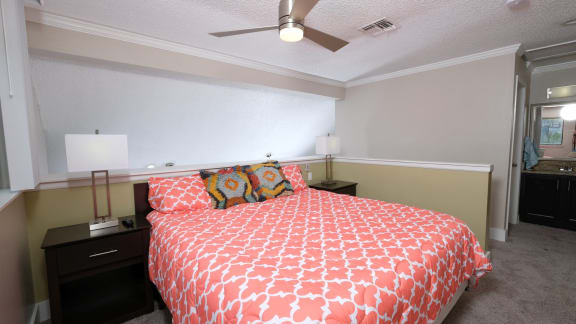 Bedroom in furnished fusion Orlando apartment with large bed, night stand, and ceiling fan.