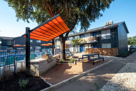 Barbecue and picnic area at Stadium 700 apartments in Arlington with large tree and gilling station