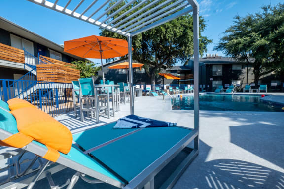 blue poolside lounge chairs with wooden shade trellis next to Stadium 700 apartments pool