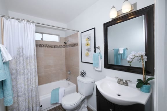 Bathroom in Fifteen 50 apartments in Las Vegas with custom tile, large mirror, and pedestal sink