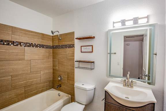 Bathroom in Fifteen 50 apartments in Las Vegas with custom tile, large mirror, and new vanity