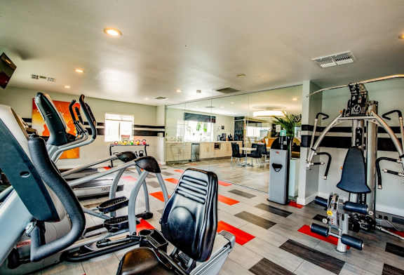A gym with a variety of equipment including treadmills, stationary bikes, and weight machines.