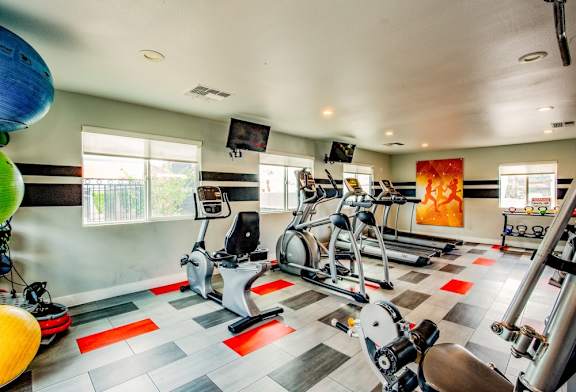A gym with a variety of exercise equipment including treadmills, stationary bikes, and weight machines.