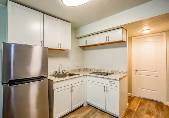 Kitchen in Fifteen 50 apartments in Las Vegas with black appliances, white cabinets, and granite-style countertops