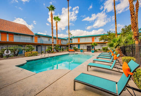 A pool area with lounge chairs and palm trees.