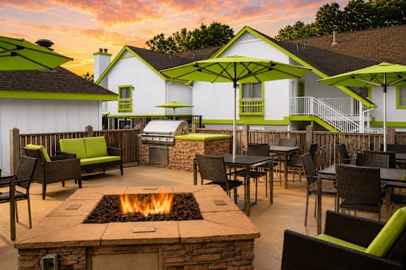 A patio with a fire pit and chairs.