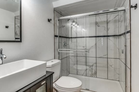 Fusion Fort Worth Apartments bathroom with walk-in shower and a sink and a toilet