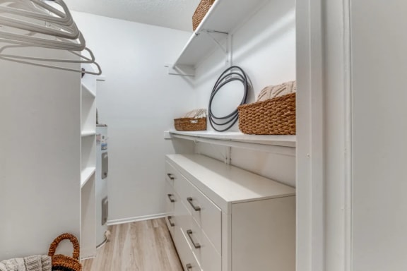 Walk-in closet in Fusion Fort Worth apartments in haltom city Texas with large dresser and storage shelves.