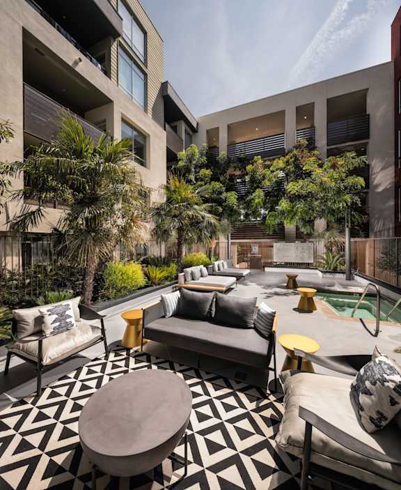 A modern outdoor living space with a black and white geometric floor, a pool, and a variety of seating options.