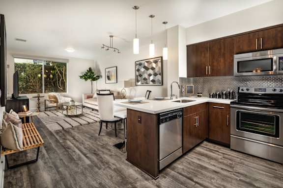 A modern kitchen with dark wood floors and stainless steel appliances.