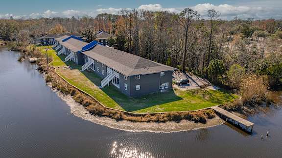 A large building sits on a small island in the middle of a body of water at Mandarin Bay Apartments Jacksonville.