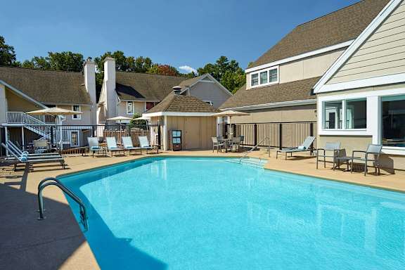 A large swimming pool surrounded by lounge chairs and buildings.