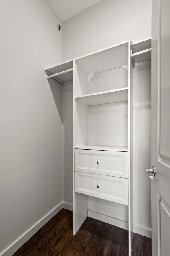 A white closet with a drawer underneath the shelves.