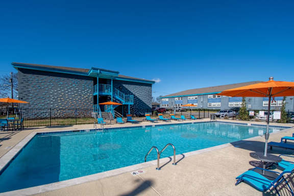 A large swimming pool at The Canvas Apartments Nashville with a blue tiled building in the background.