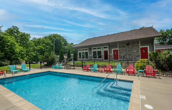 The Retreat at Indian Lake in Hendersonville TN swimming pool with red chairs and a building in the background.