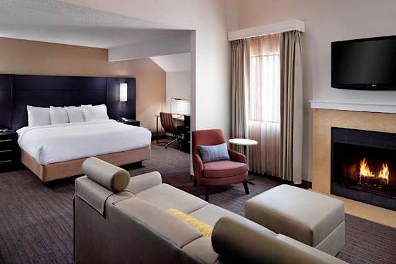 A hotel room with a large bed, a fireplace, and a television.