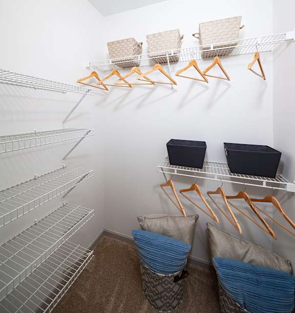 a walk in closet with white walls and white metal shelves