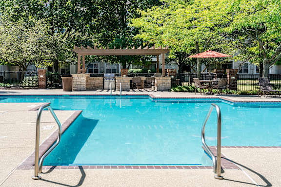 A pool with a diving board and a gazebo in the background.