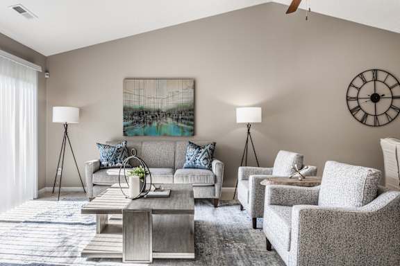 A living room with a grey couch, two chairs, a coffee table, and a painting on the wall.