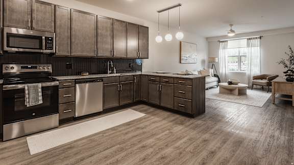 A modern kitchen with dark wood cabinets and stainless steel appliances.