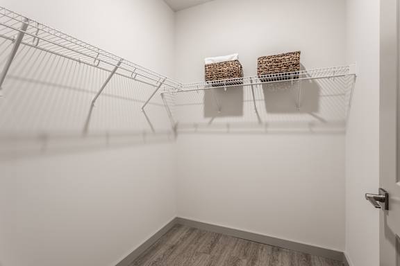 A white room with a wire shelving unit and two baskets on the shelf.