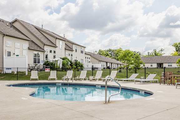 A swimming pool surrounded by lounge chairs and apartment buildings.